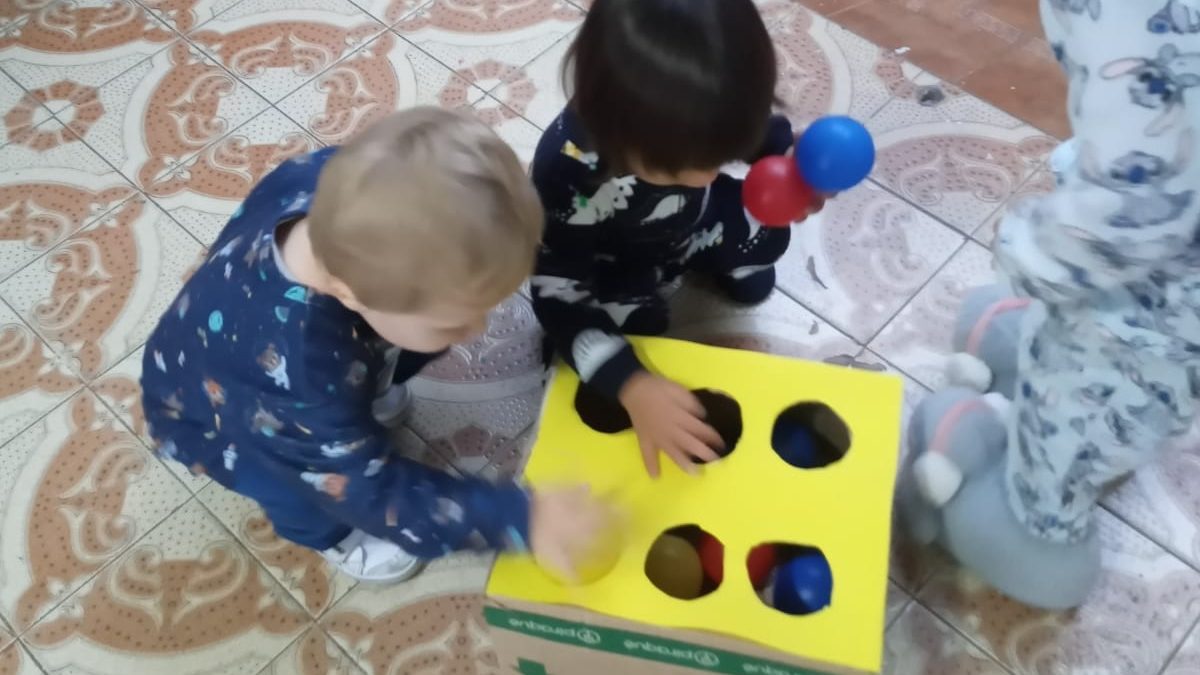 Bebês do Berçário brincando com caixa de encaixe de formas
