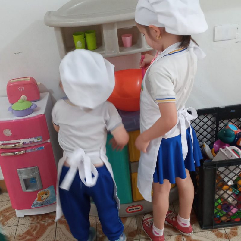 Crianças com chapéu de cozinheiro na cozinha de brinquedo