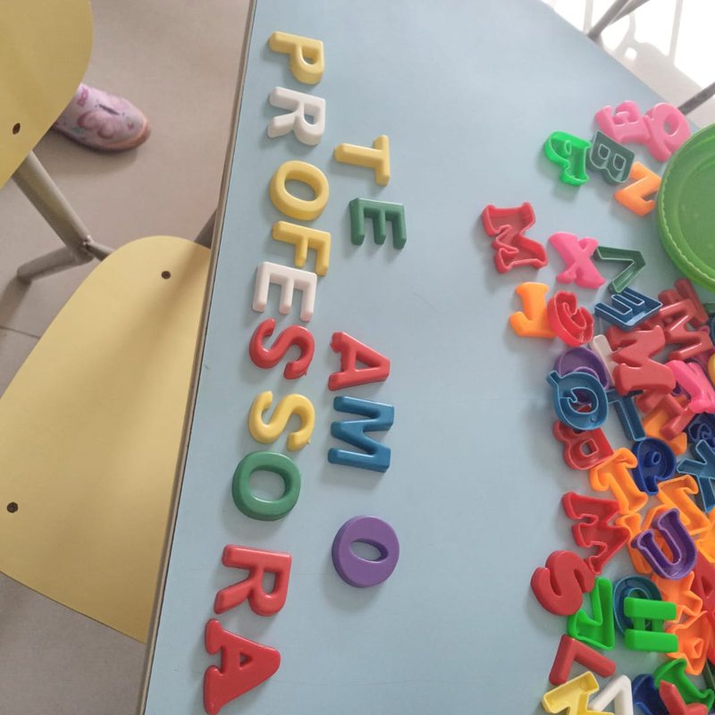 Letras coloridas formando “Te amo professora” sobre a mesa da sala